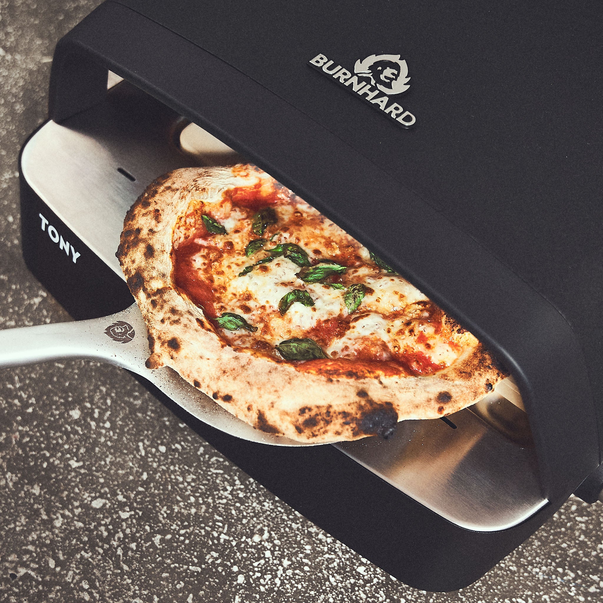 Afgewerkte pizza wordt uit de pizzaoven gehaald + 946535 Afgewerkte pizza wordt uit de pizzaoven gehaald + 946535