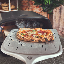 Kant-en-klare pizza wordt uit de oven gehaald met een pizzaschep