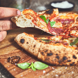 946411, 946593 Afgewerkte pizza wordt van de acaciahouten pizzaplaat gehaald