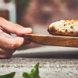 946411  Tafereel Pizzaschotel met gebakken pizza wordt opgetild