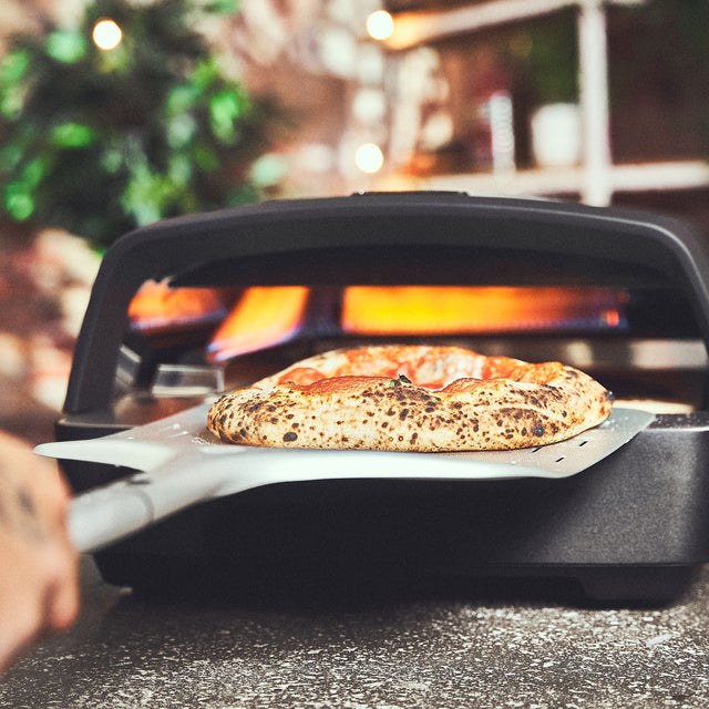 Kant-en-klare pizza wordt uit de oven gehaald met een pizzaschep