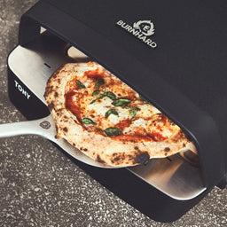 Afgewerkte pizza wordt uit de pizzaoven gehaald + 946535